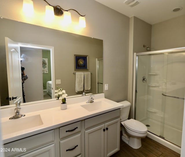 bathroom featuring toilet, an enclosed shower, vanity, and hardwood / wood-style floors