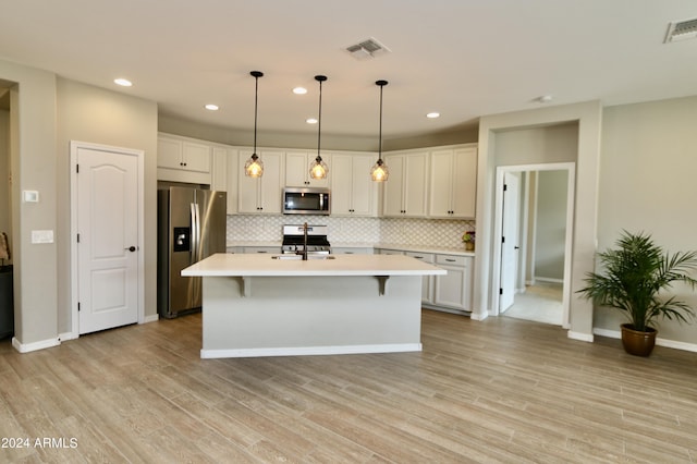 kitchen with stainless steel appliances, white cabinetry, a center island with sink, and pendant lighting