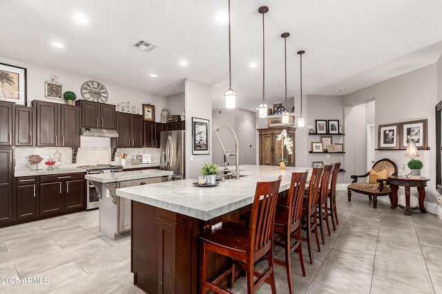 kitchen with backsplash, a spacious island, hanging light fixtures, appliances with stainless steel finishes, and a breakfast bar area