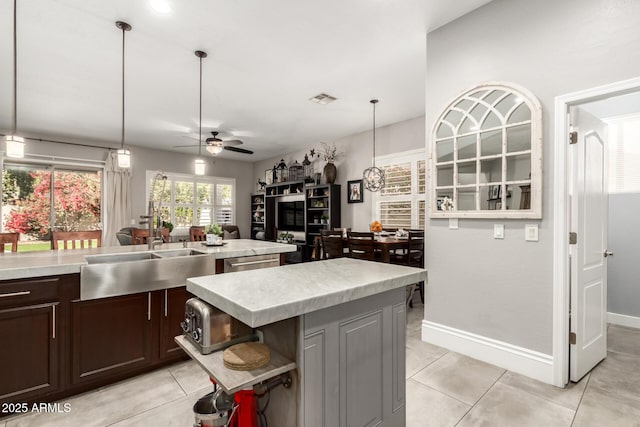 kitchen with ceiling fan, decorative light fixtures, sink, and a center island