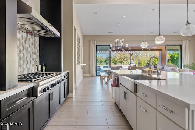 kitchen with backsplash, sink, wall chimney range hood, decorative light fixtures, and white cabinets