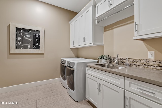 laundry room with cabinets, washing machine and dryer, and sink