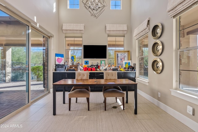 tiled office featuring a towering ceiling, an inviting chandelier, and a healthy amount of sunlight