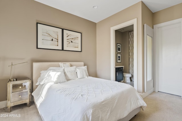 bedroom featuring ensuite bathroom and light colored carpet