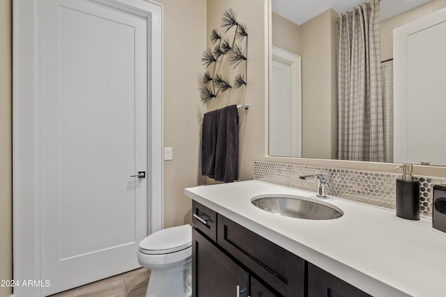 bathroom with hardwood / wood-style floors, decorative backsplash, toilet, and vanity