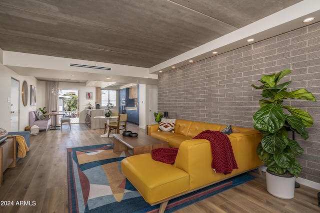 living area with brick wall and wood finished floors