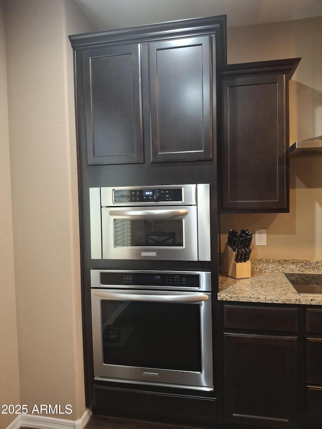10773 W Prickly Pear Trl, Peoria, AZ 85383 - kitchen with double oven, dark brown cabinets, light stone countertops, and black electric cooktop