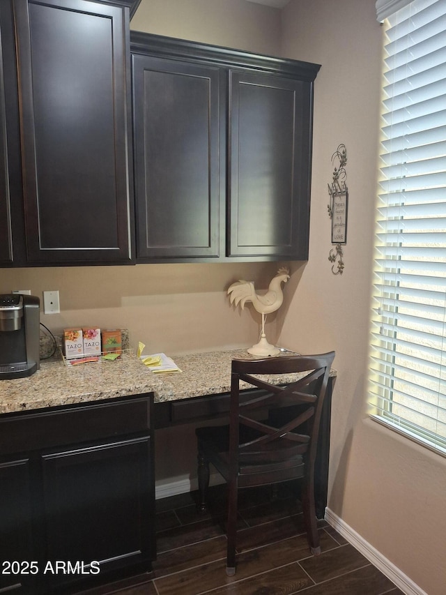10773 W Prickly Pear Trl, Peoria, AZ 85383 - kitchen featuring built in study area, wood finish floors, and light stone counters