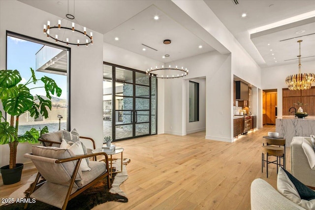 sitting room with recessed lighting, a notable chandelier, light wood-style floors, and plenty of natural light