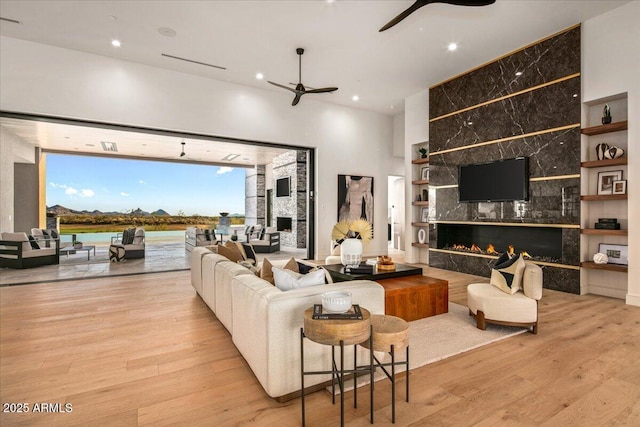 living area featuring recessed lighting, wood finished floors, a ceiling fan, and a premium fireplace