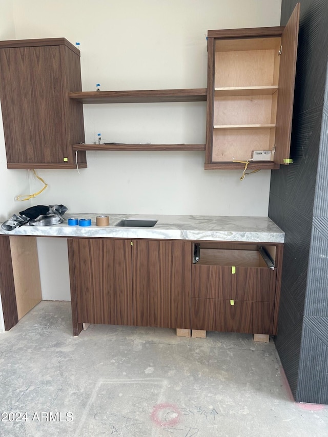 kitchen with open shelves, light stone counters, and concrete floors