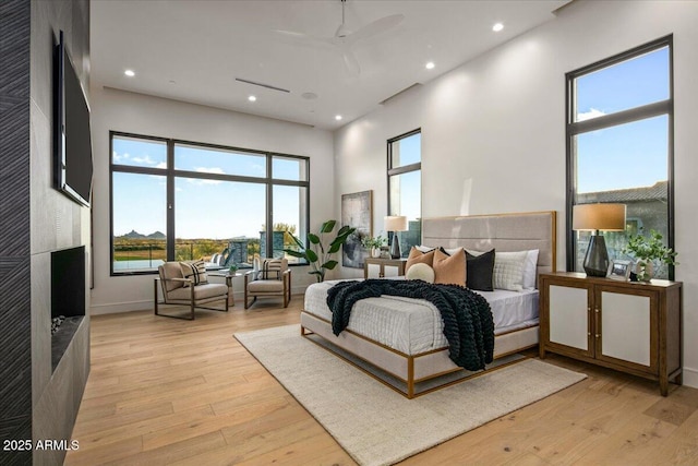 bedroom with recessed lighting, baseboards, light wood-style flooring, and a towering ceiling