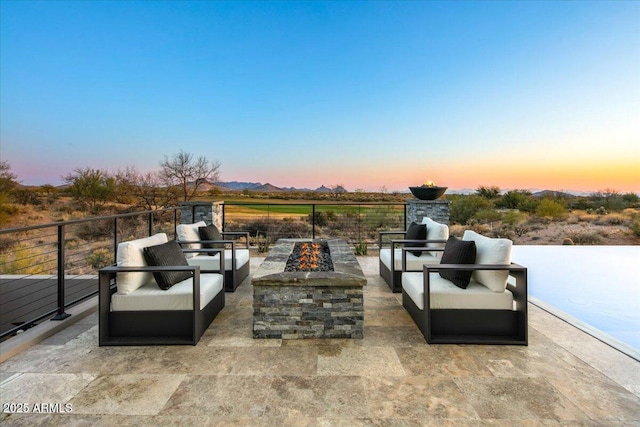 patio terrace at dusk with an outdoor living space with a fire pit