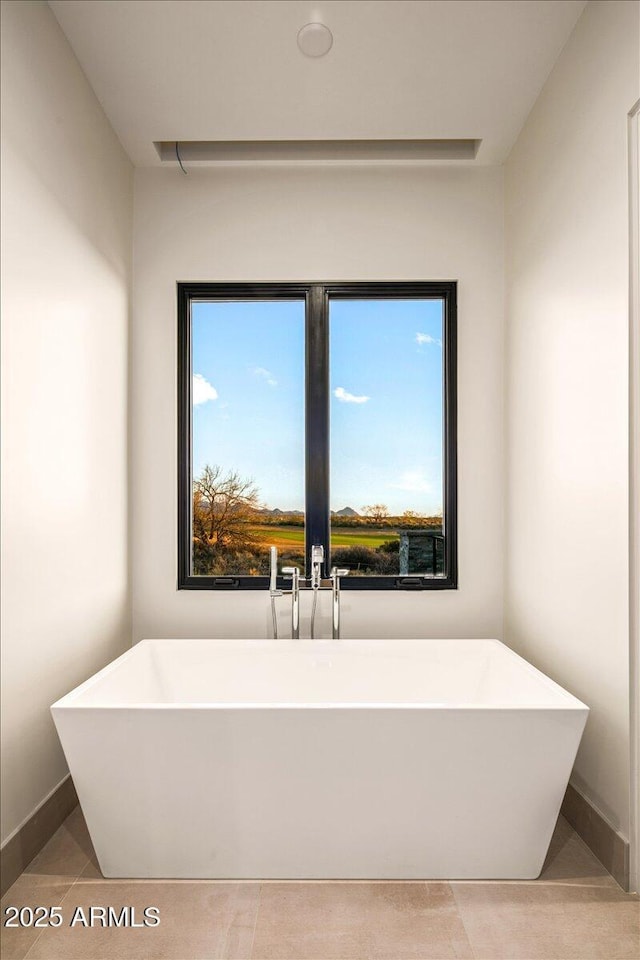 full bath featuring a soaking tub and baseboards