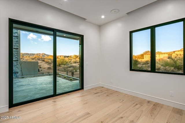 unfurnished room featuring recessed lighting, wood finished floors, and baseboards