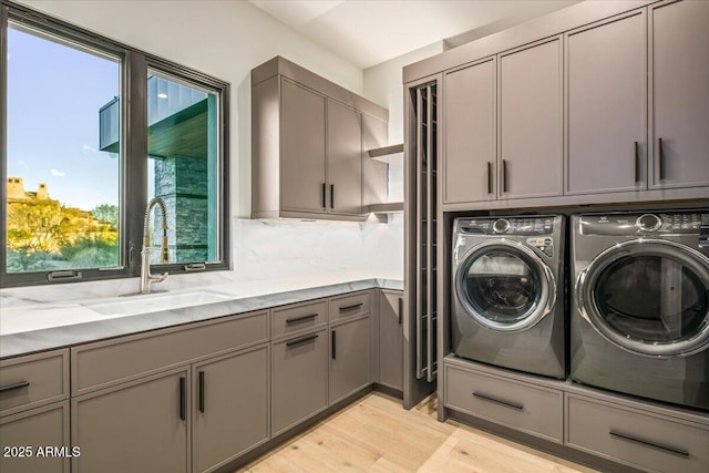 washroom featuring a sink, light wood-type flooring, cabinet space, and separate washer and dryer