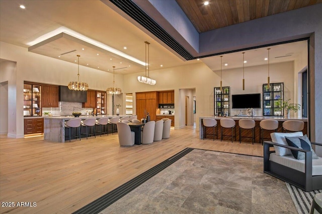 living area featuring recessed lighting, a notable chandelier, light wood-style floors, and a towering ceiling