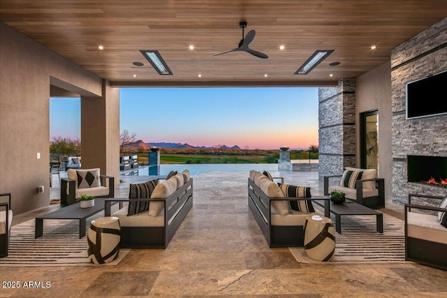 view of patio with an outdoor living space with a fireplace and ceiling fan