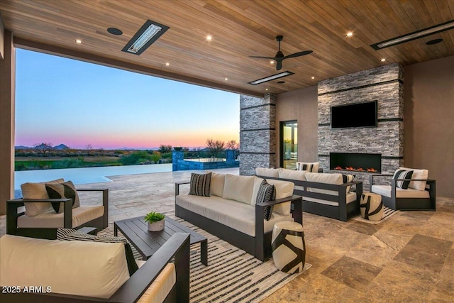 patio terrace at dusk with an outdoor living space with a fireplace, a water view, and ceiling fan