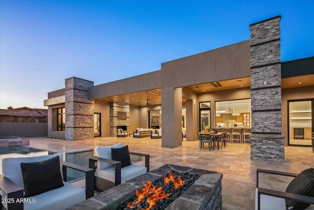 view of patio with an outdoor living space with a fireplace and a pool with connected hot tub