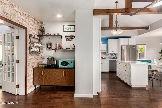 kitchen featuring appliances with stainless steel finishes, beam ceiling, white cabinets, and dark wood finished floors