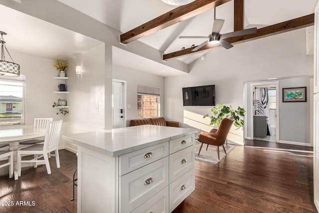 kitchen with lofted ceiling with beams, dark wood-style flooring, a center island, white cabinets, and light stone countertops