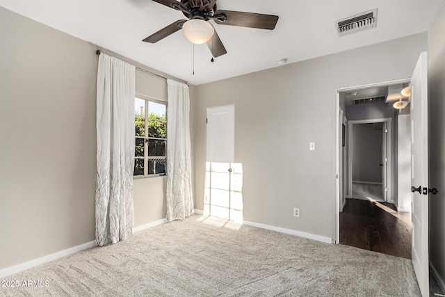 carpeted spare room with visible vents, ceiling fan, and baseboards