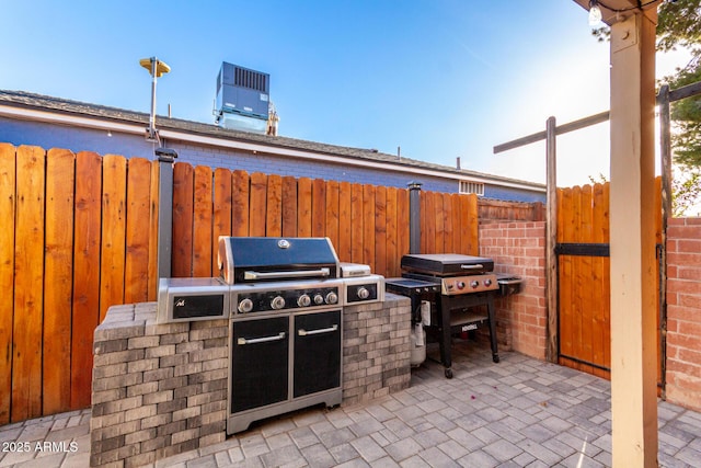 view of patio with a grill, fence, cooling unit, and area for grilling