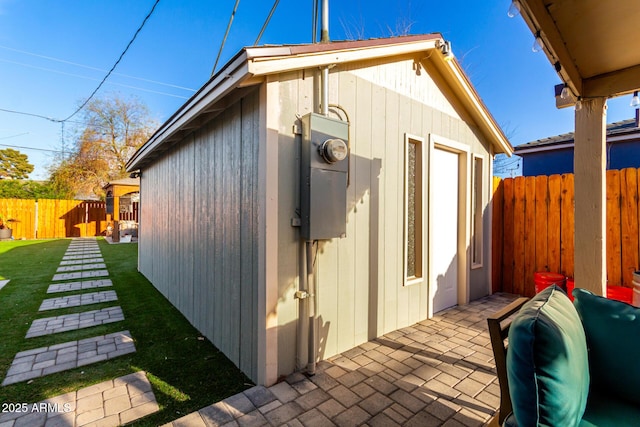 exterior space featuring a fenced backyard, an outbuilding, a lawn, and a patio