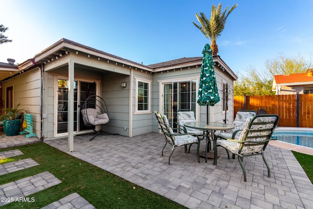 rear view of property featuring a patio area, fence, and a fenced in pool