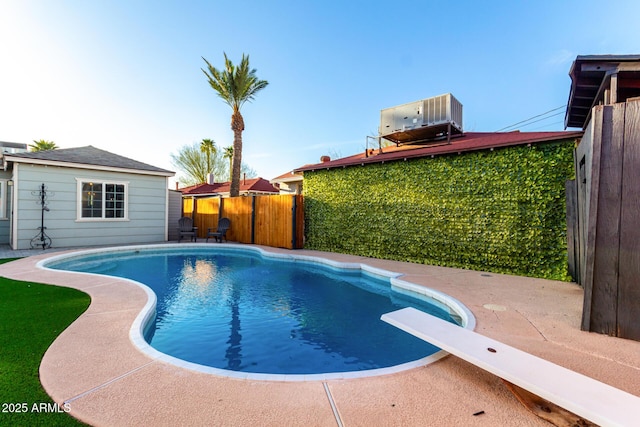 view of swimming pool featuring a fenced in pool, a fenced backyard, an outdoor structure, a diving board, and central AC