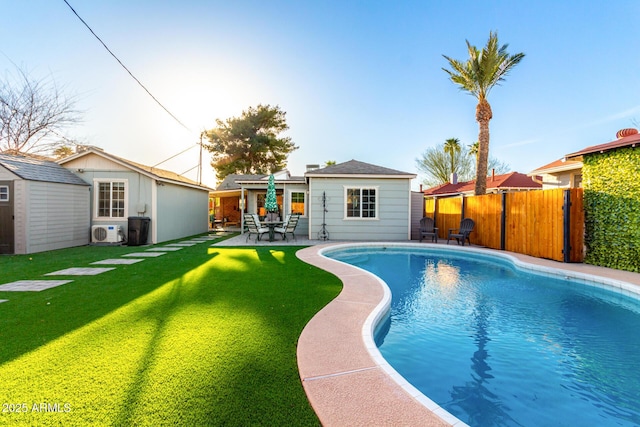 view of pool featuring a fenced in pool, an outbuilding, a patio, a lawn, and fence