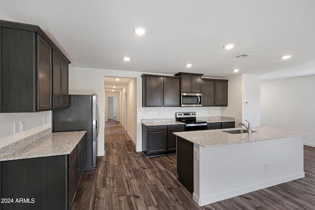 kitchen with dark hardwood / wood-style flooring, dark brown cabinets, stainless steel appliances, a kitchen island with sink, and sink