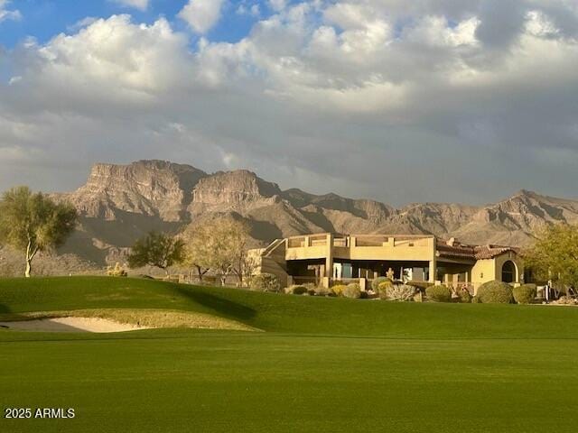 view of home's community with view of golf course, a lawn, and a mountain view