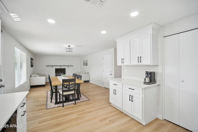 dining space featuring recessed lighting, a brick fireplace, visible vents, and light wood finished floors