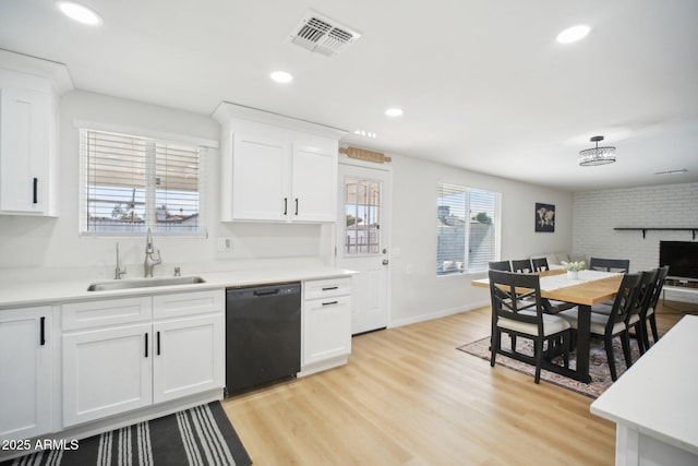 kitchen with a sink, visible vents, white cabinets, black dishwasher, and light wood finished floors