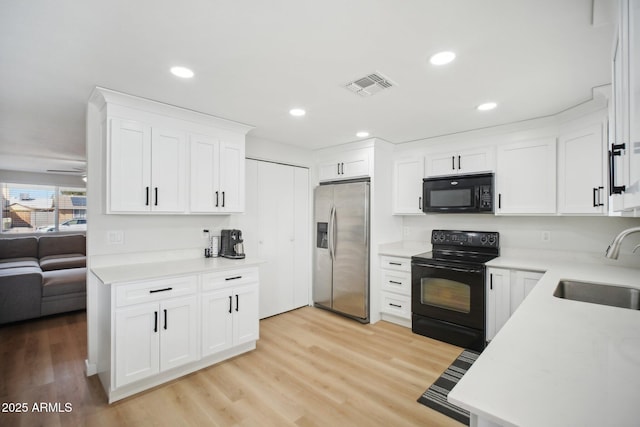 kitchen with light countertops, a sink, and black appliances