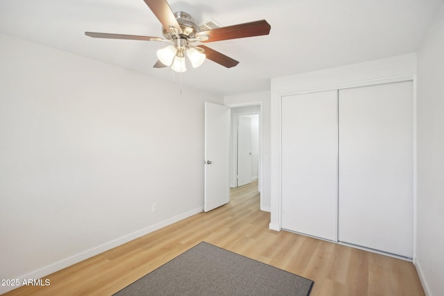 unfurnished bedroom featuring baseboards, a closet, a ceiling fan, and light wood-style floors