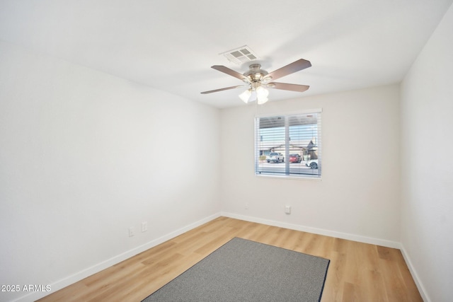 empty room featuring a ceiling fan, light wood-type flooring, visible vents, and baseboards