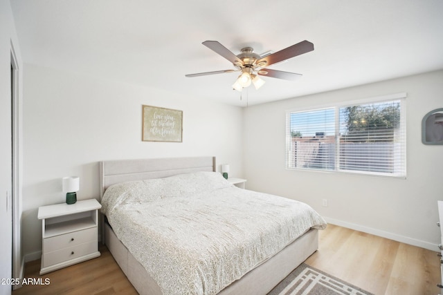 bedroom with ceiling fan, baseboards, and wood finished floors