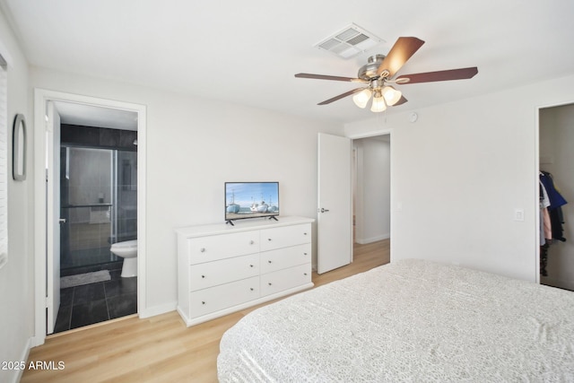 bedroom featuring light wood-type flooring, ceiling fan, visible vents, and ensuite bathroom