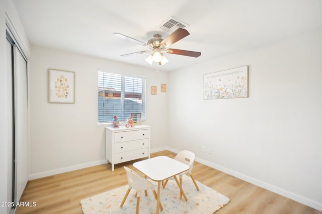 sitting room featuring light wood-style flooring, a ceiling fan, visible vents, and baseboards