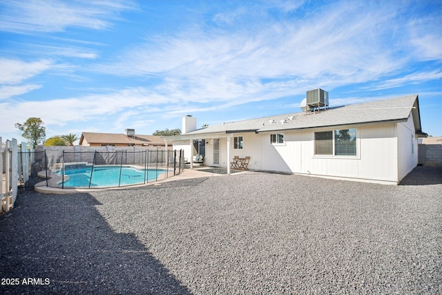 rear view of property featuring a fenced in pool, a patio area, a fenced backyard, and central air condition unit