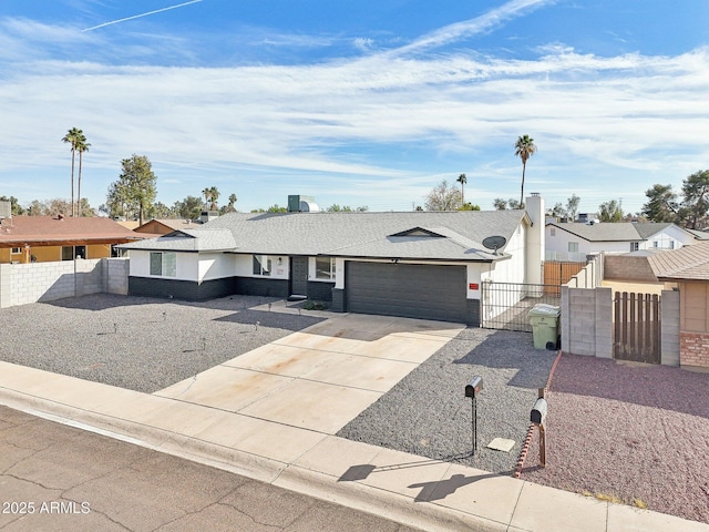 ranch-style house with a garage, concrete driveway, fence, and a gate