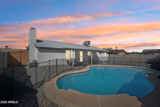 pool at dusk with a patio area, a fenced backyard, and a fenced in pool