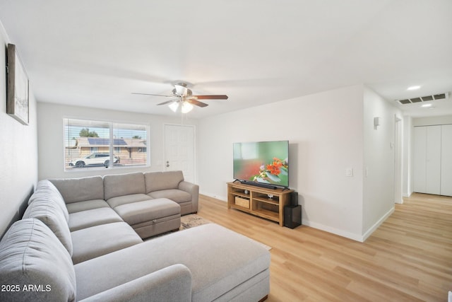 living room featuring light wood finished floors, baseboards, visible vents, and a ceiling fan