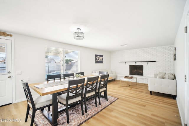 dining room with light wood-type flooring, a fireplace, and baseboards