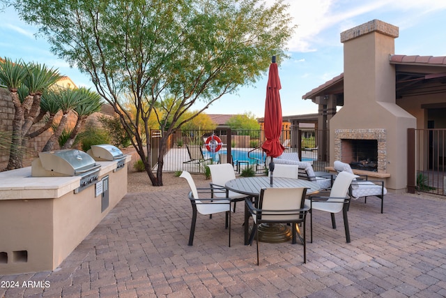 view of patio with area for grilling, exterior fireplace, and a grill