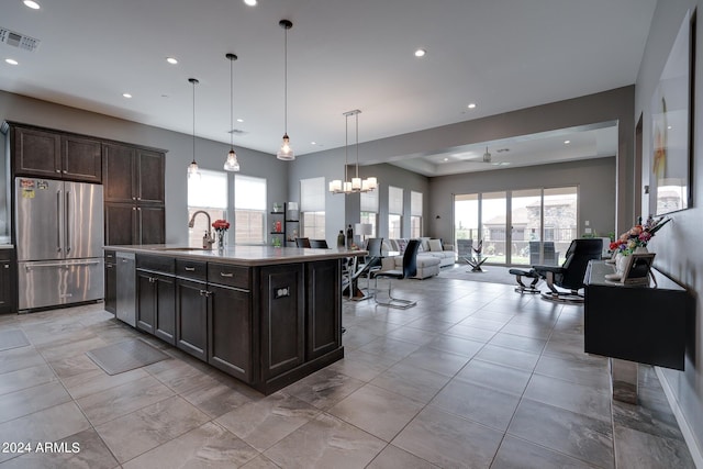 kitchen featuring stainless steel appliances, sink, pendant lighting, a center island with sink, and dark brown cabinets