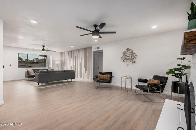 living room featuring ceiling fan and light hardwood / wood-style flooring